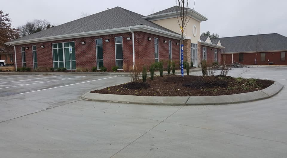 Exterior of a brick commercial building for a health clinic with large windows and a concrete parking lot.