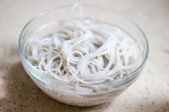 Bạn có thể chọn bất cứ loại miến nào tùy theo sở thích, ở đây mình dùng miến khoai lang. Miến ngâm nước ấm cho nở mềm. Tỏi bóc vỏ thái nhỏ, ớt khô thái nhỏ. Làm nóng dầu ăn trong chảo. Phi thơm tỏi và ớt khô. Cho bắp cải thái sợi vào đảo đều.