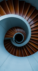 Abstract Top-Down View of a Modern Architectural Spiral Staircase with Wood Treads and Concrete Railing
