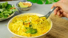 Tô bún nước kèn nóng hổi, nghi ngút khói thơm nức mũi với những miếng cá vàng ươm đang hòa quyện vào từng sợi bún thơm mềm, trắng tinh thấm đều trong nước dùng màu vàng sền sệt, điểm thêm chút màu xanh của dưa leo và rau thơm tạo nên sự hài hòa đẹp mắt và hấp dẫn.