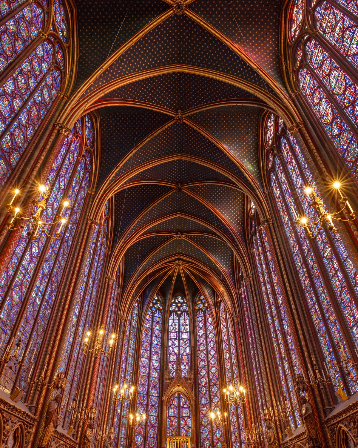 Upper chapel of Sainte-Chapelle in Paris with towering Rayonnant Gothic stained-glass windows and starry blue vault