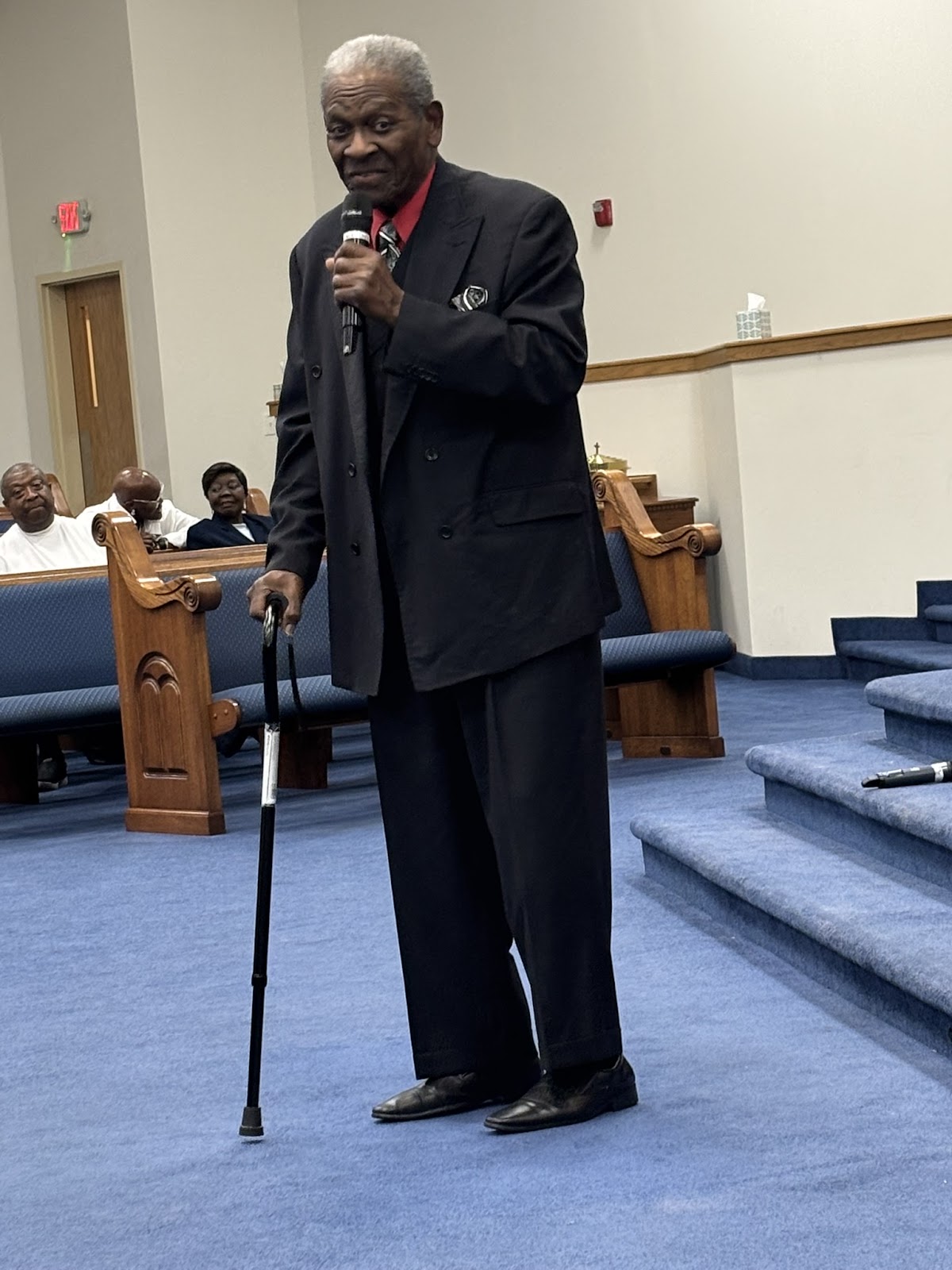 Senior minister with cane addressing the congregation during Homecoming 2026 at Sharpe Road Church of Christ