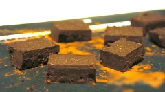 Tiếp tục, dùng dao cắt bột chocolate đen thành những hình vuông. Lưu ý là hình vuông này nhỏ hơn miếng bánh màu vàng ở step 3.