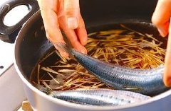 Tiếp theo các bạn lần lượt cho rượu trắng, nước lọc, rượu mirin, đường và xì dầu vào một cái chảo sau đó các bạn đun to lửa. Khi nồi nước đã sôi các bạn cho gừng, cá mòi đã sơ chế sạch vào rồi đun tiếp.