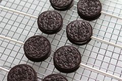 Đun cách thủy cho nóng chảy 200g chocolate trắng. Tách bánh Oreo, cho một ít chocolate chảy và giữa bánh rồi đặt ngay que kẹo vào. Chocolate sẽ có tác dụng cố định que kẹo vào bánh. Kẹp bánh trở lại. Ấn nhẹ để hai lớp bánh dính chặt với nhau. Để bánh trên khay trong 10-15 phút để chocolate cứng lại.