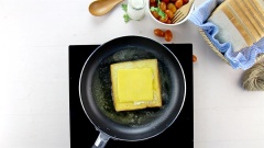 Khi lòng trắng trứng chín thì lật miếng sandwich lại, phủ lên 1 lát phô mai cheddar, tiếp theo là 100gr phô mai mozzarella, rồi thêm 1 lát phô mai cheddar nữa.