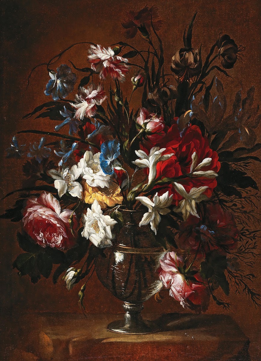 Carnations roses lilies and other flowers in a vase on a ledge