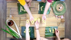 Cách làm bánh tét chữ: Đậu xanh để cho hơi nguội rồi dùng giấy bạc bọc lại thành một cuộn lớn, nhớ cuốn chặt tay để đậu xanh được dính chặt vào nhau không bị vỡ nát khi cắt và tạo hình. Gỡ bỏ giấy bạc rồi cắt đậu xanh thành những khoanh tròn dày 2cm. Cắt bìa mica thành những chữ cái theo ý nghĩa mà bạn mong muốn như: "Tết 2018", "Chúc mừng năm mới", "Vạn sự như ý", "Tấn tài tấn lộc",... Dùng bìa mica đó đặt lên khoanh đậu xanh rồi tỉa theo đường viền để tạo ra những chữ cái.