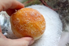 Đặt từng chiếc vòng bánh lên miếng giấy nến hình vuông (mỗi bánh 1 miếng giấy nhé), bạn chờ cho donut nở lớn thêm nữa là có thể chiên nhé. Chế dầu ngập chảo, đun nóng, sau đó cho từng chiếc bột bánh vào chiên đến khi thấy bánh chín, có màu vàng nâu đậm, giòn rụm thì vớt ra cho ráo dầu. Lăn từng chiếc bánh qua một lớp đường để chúng phủ đều bên ngoài là xong rồi đó.