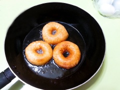 Chiên bánh donut: Bắc 1 cái chảo chống dính lên bếp, cho dầu vào, dầu nóng thì vặn lửa nhỏ vừa, gỡ giấy nến ra và cho bánh donut vào chiên, chiên cho bánh chín vàng đều mới lật mặt kia chiên tiếp cho bánh vàng đều thì vớt bánh ra.