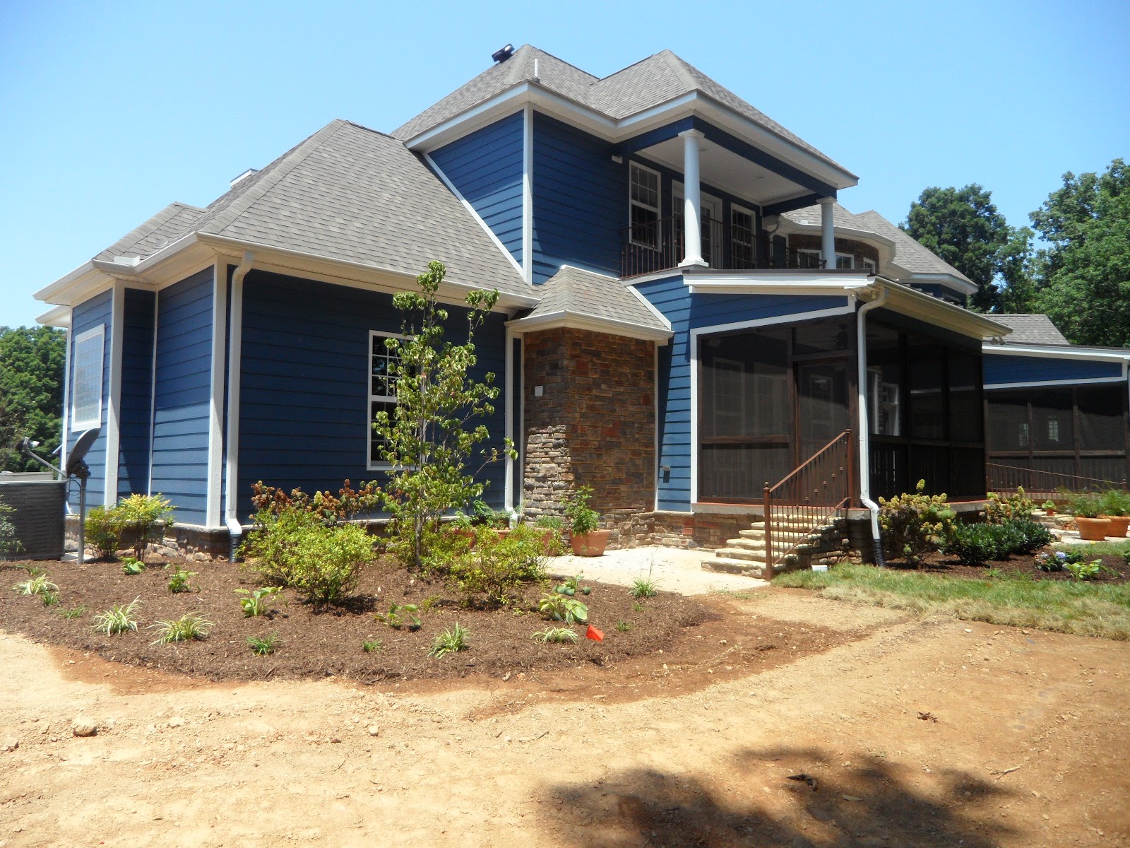 Exterior of a two-story blue house with white trim, stone accents, and a screened-in porch in East Tennessee.