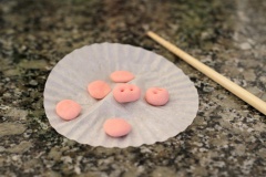 Với phần bột bánh bao còn lại, các bạn nhào với một ít phẩm màu đỏ rồi chia thành từng phần nhỏ cỡ hạt đậu, viên tròn và ấn dẹt ra để làm tai và mũi như hình bên nghen.
