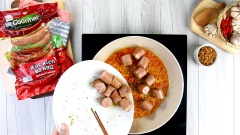 Trên chiếc chảo lúc nãy chúng ta tiếp tục cho vào 2 muỗng canh dầu màu điều, 30gr tỏi băm, 10gr ớt băm. Phi cho tỏi ớt thơm lên thì đổ xúc xích vào xào cho xúc xích săn lại, hiện ra từng cánh hoa đẹp mắt.
