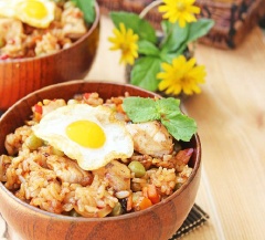 Múc cơm chiên ra tô, xếp trứng ốp la lên trên, ăn nóng.