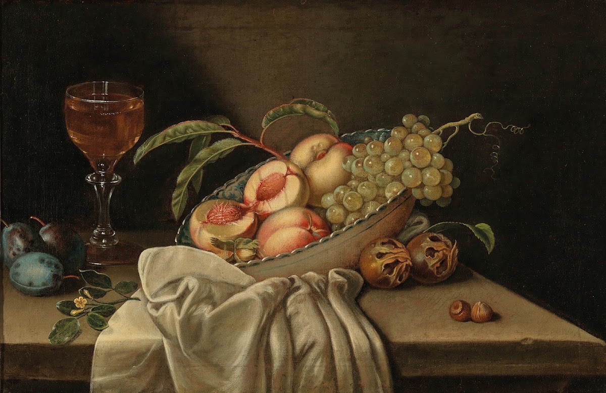 Mixed fruit in a bowl a glass of wine and a cloth on a table