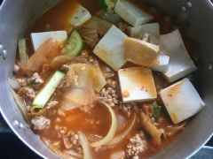 Khi nước canh sôi già thì cho bí ngòi vào. Cuối cùng cho đậu hũ thái lát vào và tắt bếp. Thả vào vài lát ớt sừng để tăng hương vị nồng nàn cho món canh kim chi.