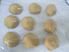 Chia bột bánh bao đường nâu thành 9 viên đều nhau, bọc màng thực phẩm, ủ khoảng 15 phút. Sau đó lấy ra vê tròn lại.