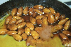 Đun sôi hỗn hợp gồm 2 muỗng canh siro, 2 muỗng canh nước, 1 muỗng canh dầu ăn vào đun đến sôi màu hơi cánh gián thì cho hạnh nhân vào hỗn hợp trên rồi đảo đều lên và đun cho đến cạn.