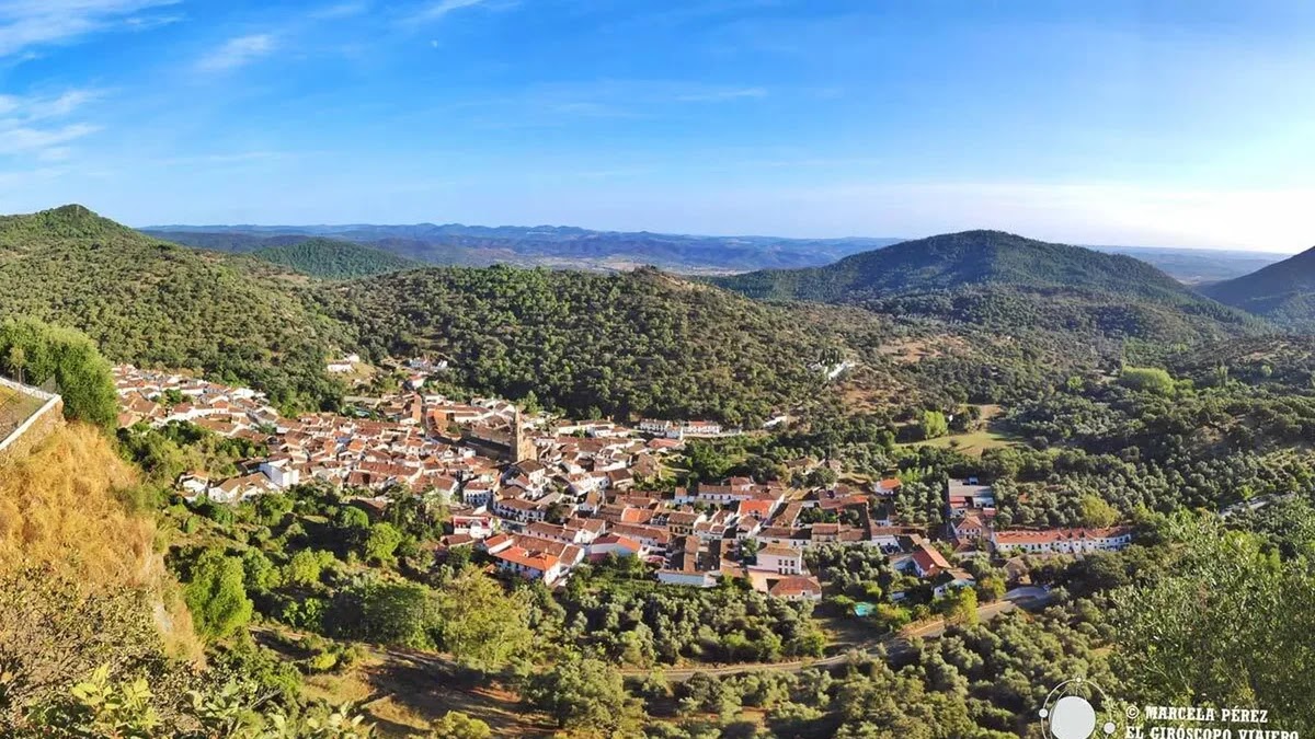 Panoramic view of the whitewashed village of Alájar nestled among green hills in the Sierra de Aracena.