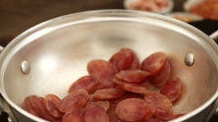 Cho 50gr lạp xưởng vào chảo, cho vào chút nước rồi chiên sơ cho lạp xưởng ra bớt mỡ. Cũng trên chảo đó, cho vào 2 muỗng canh dầu điều, 50gr đậu phộng còn vỏ và 1 muỗng cà phê muối. Rang đậu phộng trên bếp với lửa nhỏ khoảng 5 phút đến khi vàng. Băm nhỏ 50gr hành lá, cho vào chén trộn cùng 1/2 muỗng cà phê muối và 1/2 muỗng cà phê đường. Sau đó rưới dầu nóng lên để làm mỡ hành.
