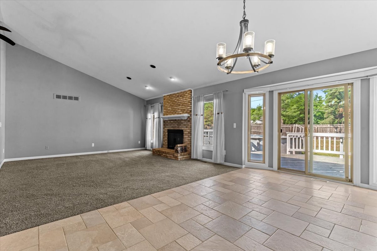 Open-concept living room with wood-burning fireplace and new carpet at 13656 Heatherwood Drive, Sterling Heights, MI