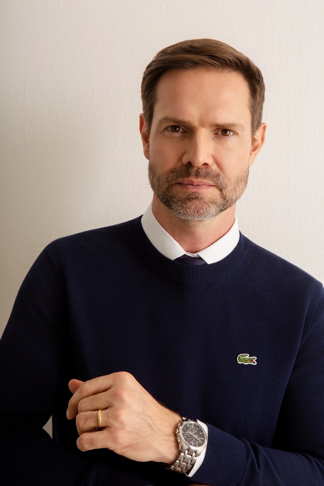 Retrato masculino colorido em meio corpo com malha azul e olhar direto.