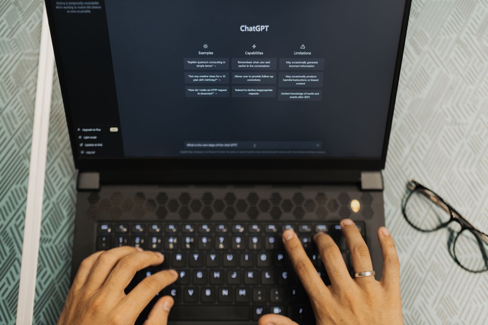 Hands typing on a laptop with ChatGPT open