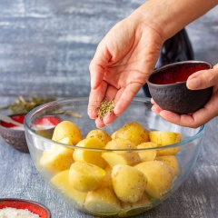 Kế tiếp cho lá hương thảo khô băm nhỏ, bột phô mai vào, đeo bao tay vào trộn đều cho khoai tây thấm gia vị. Cho khay khoai tây vào lò nướng trong khoảng 25 phút. Bạn có thể thử bằng cách xiên nĩa qua khoai tây để biết khoai chín chưa nhé!