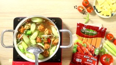 Khi canh sôi lại cho xúc xích, bạc hà, đậu bắp, giá đỗ, rau thơm và ớt tươi cắt lát vào nồi rồi khuấy nhẹ thêm 2 phút thì tắt bếp.