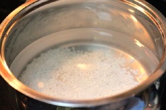 Gạo nếp đãi qua nhiều lần cho thật sạch, cho gạo vào nồi, thêm vào khoảng hai chén nước lọc, đun sôi, lửa nhỏ, thỉnh thoảng dùng muôi khuấy đều để gạo không bị dính vào đáy nồi.
