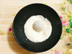 Rắc 1 chút bột bắp, lấy bột ra bàn cho nguội bớt sau đó nhồi sơ qua cho bột dẻo mịn, cắt bột thành những miếng to gấp đôi viên nhân. Làm tròn từng viên vỏ bánh sau đó ấn dẹt, đặt viên nhân bánh vào giữa, gói lại cho kín. Lăn viên bánh vừa gói vào tô bột vụn dừa để bánh bám đều 1 lớp bột vụn dừa là xong rồi đó.