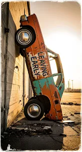 Rusted Vintage Car Art Installation Against Concrete Wall