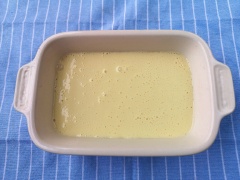 Lót một miếng giấy chống dính vào đáy khuôn bánh. Đổ hỗn hợp sữa chua bột và trứng vừa trộn vào khuôn bánh sữa chua.