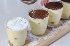 Chuẩn bị ly hoặc khuôn đựng bánh tiramisu, lấy bánh sâm panh nhúng vào hỗn hợp cà phê rượu, cho vào ly đựng, tiếp theo dùng muỗng múc kem vào, làm lần lượt 3 lớp bánh và kem. Để bánh vào tủ lạnh ít nhất 2 tiếng. Khi ăn phủ một lớp đường bột trên mặt, sau đó phủ tiếp 1 lớp bột cacao. (Phủ đường bột để lớp bột cacao không bị thấm ẩm, bánh để lâu lớp bột cacao vẫn đẹp)