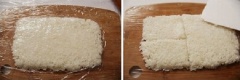 Các bạn ướp thịt bò với gừng, nước tương, tiêu trong 5-10 phút. Tiếp theo, đổ cơm ra một cái thớt sạch, nắn cơm thành hình chữ nhật, độ dày vừa phải. Sau đó, bạn trải một tấm nilon bọc thực phẩm lên trên bề mặt của cơm, dùng một con dao thật sắc và chia cơm thành 4-5 phần bằng nhau. Sau khi thịt đã ngấm gia vị, đặt một chiếc chảo lên bếp, làm nóng dầu ăn. Sau đó, bạn phi thơm hành khô, cho tiếp thịt vào đun chín. Tuy nhiên, bạn không được đảo thịt mà phải chiên thịt thành từng mê có bề rộng và chiều dài khoảng như những miếng cơm ý nhé. Như mình đã nói ở trên, vốn sẵn thịt bò đã có chất dính rồi nên khi xay nhuyễn sẽ rất dễ để chúng ta tạo hình. Bạn nhớ lật đều cả hai mặt để thịt chín và vàng đều nhé. Chiên thịt xong thì bạn cho thịt ra đĩa, để nguội bớt.