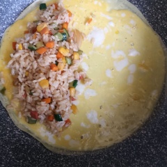 Láng đều 1 muỗng canh dầu ăn trong chảo. Đánh tan 1 quả trứng vịt rồi cho vào dàn đều, chiên chín. Sau đó cho cơm chiên vào nằm gọn ở 1 bên miếng trứng, gặp nửa cọn lại phủ kín lên trên cơm chiên.