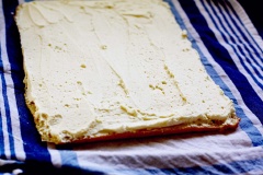 Nhân phô mai: Cho phô mai Mascarpone, đường bột, mật ong, kem heavy cream vào trộn đều ở tốc độ trung bình khoảng 1 phút cho đến khi kết hợp mịn nhuyễn. Sau khi bánh đã nguội gỡ khăn ẩm ra, quết kem phô mai lên một lớp mỏng, cuộn tròn đều. Rây một lớp đường bột lên trên. Sau đó dùng dao cắt lại cho đều bánh.