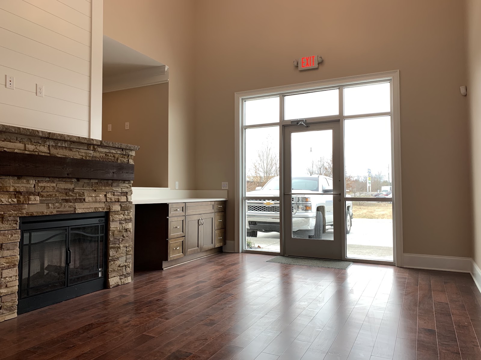 Interior view of a health clinic featuring a stone fireplace, wood-look flooring, and a glass entry door with an exit sign.