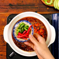 Cho tiếp, 50gr tôm khô đã ngâm mềm với 40gr ớt hiểm và 30gr tiêu xanh vào kho thêm vài phút thì tắt bếp, rắc hạt tiêu lên trên.