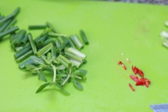 Hành lá nhặt rửa sạch, phần đầu hành trắng thì cắt lát mỏng, phần lá hành cắt khúc cỡ 2cm. Ớt cắt lát mỏng. Ngò om cắt ngắn.