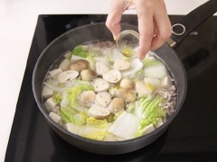 Tiếp theo, cho đậu hũ non, nấm rơm, cải thảo, miến vào, nấu đến khi sợi miến mềm là được. Nêm 1 muỗng canh nước mắm vào cho vừa ăn.