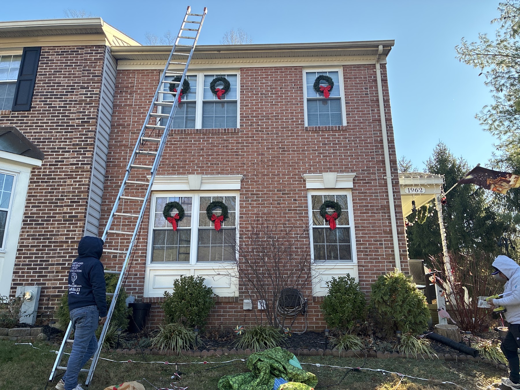 Holiday Lights DMV team setting up an extension ladder during a real installation