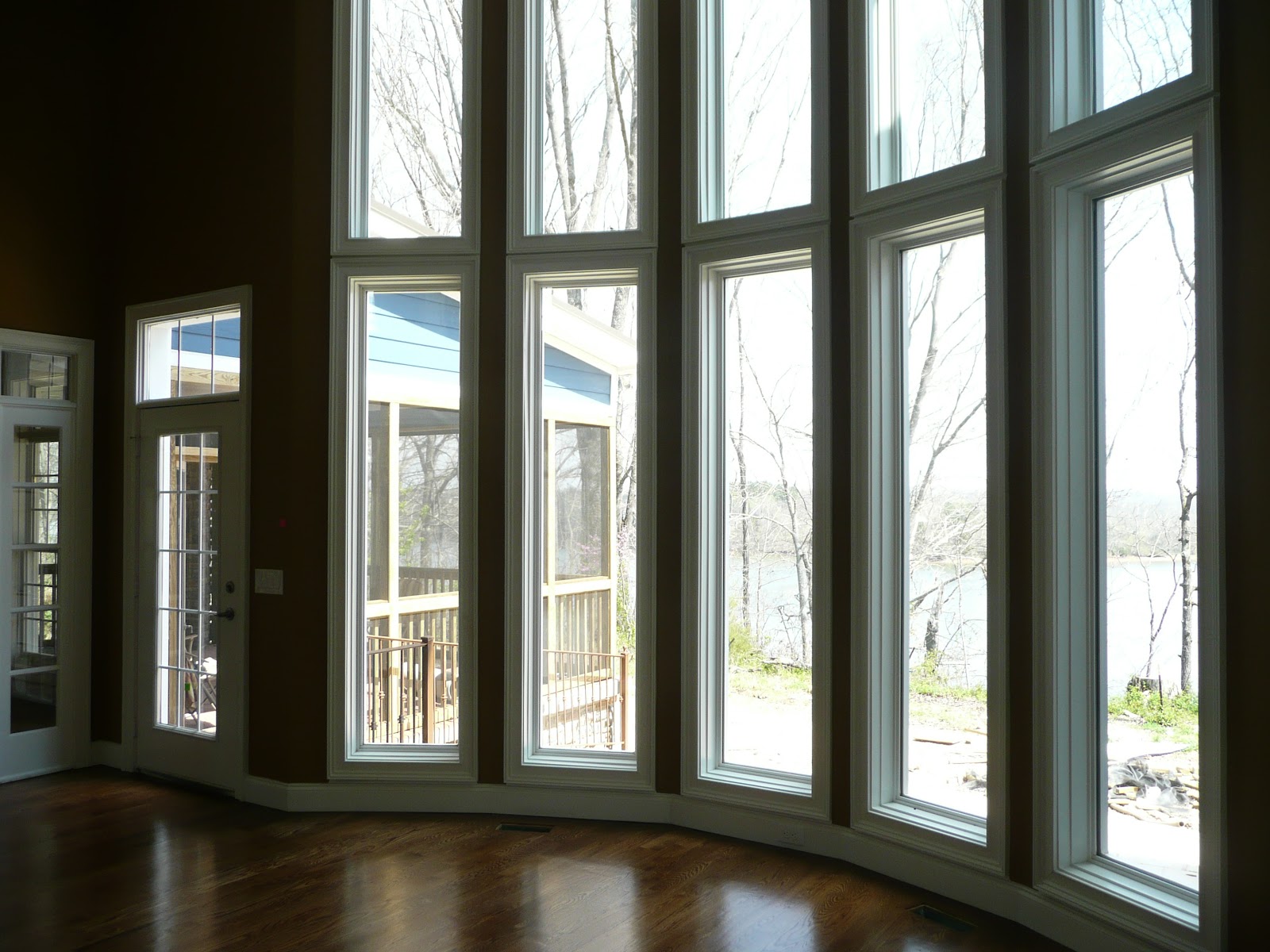 A curved wall of tall, narrow windows overlooking trees and water in a residential interior in East Tennessee.