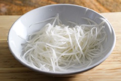 Củ cải trắng gọt vỏ, rửa sạch, dùng dụng cụ bào thành sợi dài. Hành lá rửa sạch, cắt nhỏ.