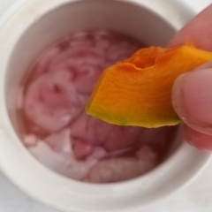 Cho bí đỏ đã cắt vào 1 góc chum óc heo. Hành lá + ngò rí cắt nhuyễn cho lên mặt óc. (nếu người lớn ăn thì cho thêm ít tiêu xay và hành tím cắt lát thì óc sẽ thơm hơn). Đậy nắp chum lại.