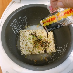 Gạo vo sạch, cho vào nồi cơm điện, chế nước vừa đủ theo mức gạo. Sau đó cho mì ramen vào kèm theo các gói gia vị, rau của mì. Bật nút nấu và chờ cơm cùng mì chín. Khi cơm đã chín, mở nắp ra, xới trộn lên là có thể thưởng thức nha.