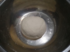 Cho bột vào thố lớn, thêm 1g muối và nước vào, dùng đũa khuấy đều. Sau đó dùng tay nhồi hỗn hợp bột thành khối đồng nhất, bọc màng thực phẩm ủ 1 tiếng đồng hồ. Sau khi ủ, chia chỗ bột thành 7 khối đều nhau, vê tròn.