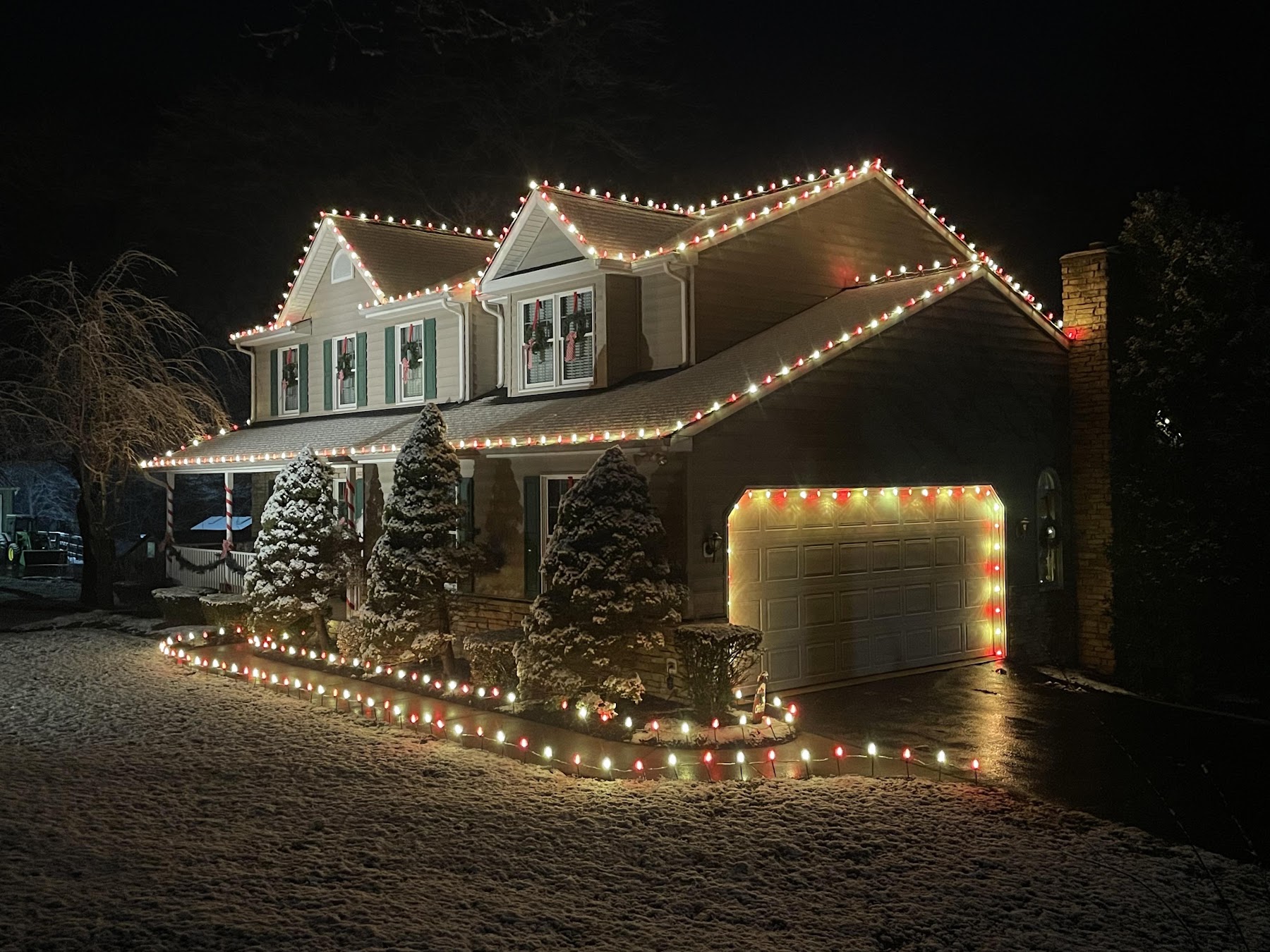 Real completed red-and-warm-white Christmas light display on a snow-covered home