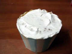Đánh bông 200ml kem sữa tươi rồi phết 1 ít lên mỗi bánh cupcake lớn. Bóc vỏ cupcake nhỏ, đặt lên trên cupcake lớn. Cắt chéo bớt viền trên của cupcake để tạo hình khung tròn.