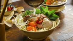 Cách dùng bánh đồng tiền - súp bánh phồng: Xếp bánh phồng, giá, rau và hẹ lên tô, thêm bò viên, bò tái, nấm kim châm và chế phần nước dùng đến xâm xấp mặt tô. Thêm tỏi phi, hành lá và ớt xắt vào cho thơm hơn nữa nhé.